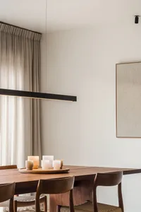 Modern minimalist dining room with wooden furniture and candles on a wooden table.