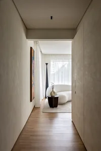 A modern minimalist interior with a curved white sofa, wood floor, and abstract painting on the wall.