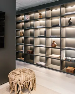 A modern minimalist living room featuring a black metal bookshelf filled with books, art, and decorative objects.