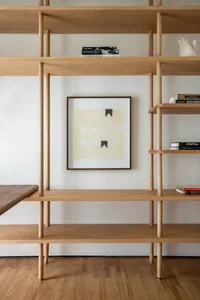A modern minimalist shelving unit made of wood with a framed abstract art print featuring a black and white design.