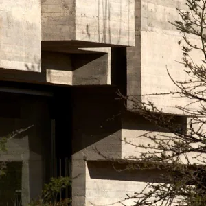 A modernist residential building with a concrete exterior, featuring geometric shapes and shadows.