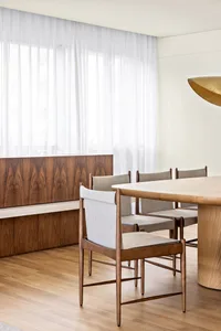 A modern residential dining room featuring a wooden table and chairs.