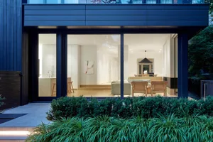 Modern residential interior with large glass walls and wooden furniture.