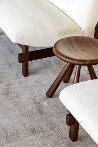 A modern white sofa with a wooden stool beside it on a textured carpet.