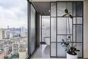 Modern minimalist bathroom featuring glass walls, concrete tiles, and a white bathtub.