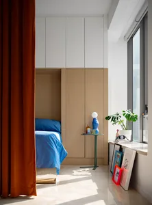A minimalist bedroom with a white wood cupboard and blue bedding.