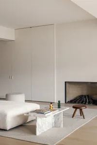 Minimalist living room with a marble coffee table, wood stools, and a fireplace.