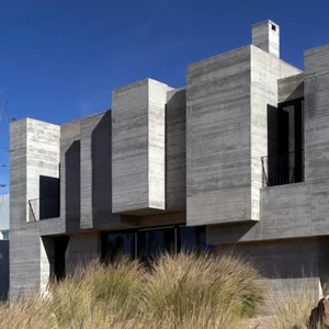 Modern residential house with concrete exterior walls and large windows.