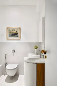 Modern bathroom with white marble sink, toilet, and wall art