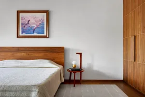 A modern minimalist bedroom featuring wooden furniture and a textured white bedspread.