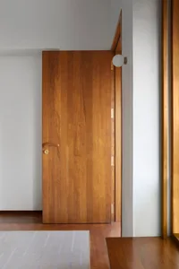 Closed wooden door with a brass handle and lock, situated in a modern interior design setting.