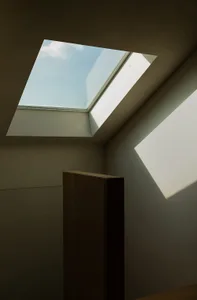 A minimalist interior showing a white ceiling with a metallic cabinet.
