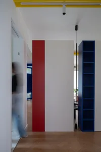 A minimalist interior with white walls, a red pillar, and blue shelves.