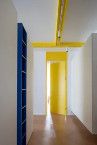 Modern space with blue shelves, yellow accents, and wooden flooring.