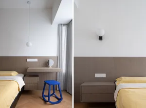A modern bedroom with brown and neutral tones featuring a floating desk, blue stool, and yellow bedding.