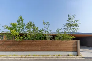 A minimalist modern house with a concrete facade and a wooden fence.