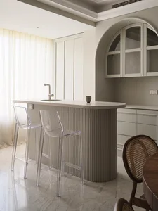 Modern kitchen with concrete island, bar stools, and sleek design.