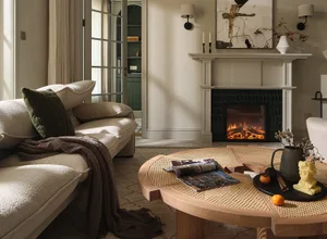 A modern living room featuring a rattan table, comfortable seating, and a cozy fireplace.