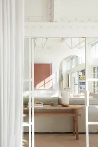 A modern minimalist living room with wood, glass, and fabric elements.