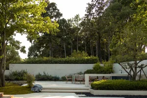 A modern outdoor patio featuring concrete, plants, and stone garden beds.