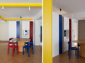 A modern residential kitchen with a wooden table and chairs, featuring a blue and red color scheme.