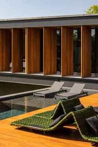 Luxury patio furniture featuring glass, wood, and fabric materials for outdoor relaxation.
