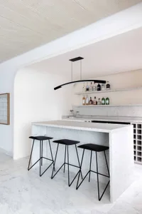 A minimalist bar counter made of granite with black stools.