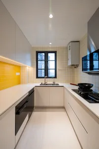 Modern kitchen with yellow tile backsplash and white countertops, featuring a black range hood and stainless steel appliances