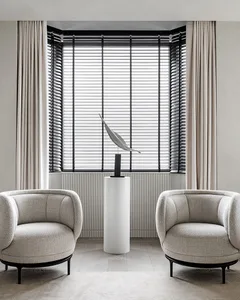 Modern living room featuring minimalist furniture and a sleek, white pedestal sculpture with a leaf-like design.