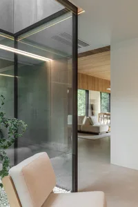 Modern living room with concrete walls, glass walls, and wooden furniture.