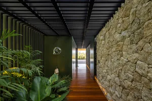 A modern minimalist hallway with stone and wooden walls and a wooden floor, featuring a sleek design with a glass light fixtu