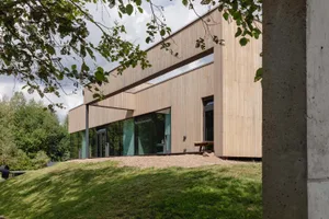 Modern residential exterior featuring wooden siding and large glass windows.