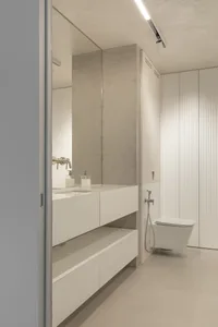 Modern minimalist bathroom with concrete walls and white ceramic fixtures.