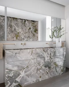 A minimalist bathroom featuring marble walls and countertops with natural light.