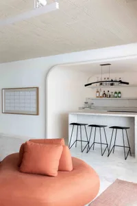 Spacious modern living room with large circular peach-colored lounge chair and concrete bar area with shelves and black stool
