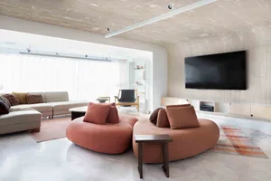 A modern living room featuring a circular sofa with textured upholstery, white walls with vertical detailing, and a large win