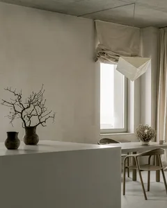 A minimalist residential interior featuring concrete walls and a large window with curtains.