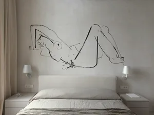 A minimalist bedroom featuring a bed with a white headboard and linens, a wall drawing of a reclining figure, and bedside lam