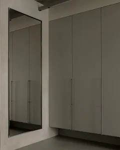 A minimalist interior design featuring a concrete wall and floor, with a large mirror and a cabinet.