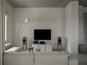 A minimalist living room with concrete walls, a large sofa, and floor-to-ceiling windows.