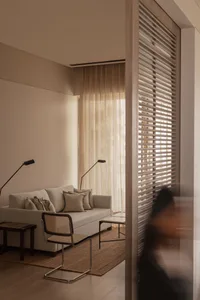 A minimalist living room with light-colored fabric curtains, wooden furniture, and a modern coffee table.