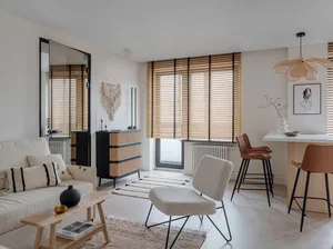 A minimalist living room featuring wood furnishings and fabric accents.