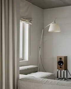 Minimalistic living room with a gray sofa, a floor lamp, a window with curtains, and a speaker.