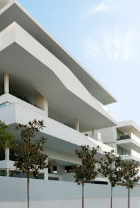 A modern, mixed-use development featuring white concrete structures with glass elements.