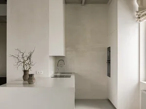 A minimalist kitchen featuring modern design elements with a concrete countertop and white cabinets.