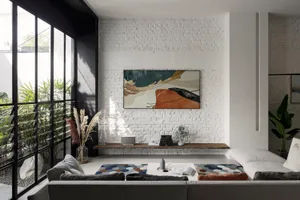 A modern living room featuring concrete and brick walls, a white sofa, and a large abstract painting on the wall.