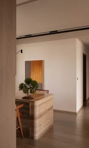 A modern, minimalist dining room featuring wooden furniture and a bonsai tree.
