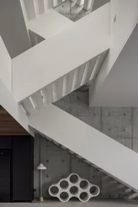 Modern minimalist white space featuring concrete walls and white staircase.