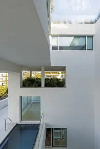 Modern residential architecture with minimalist design, featuring white concrete walls and sleek lines.