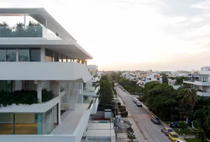 Modern apartment building with glass and concrete exteriors and white balconies.